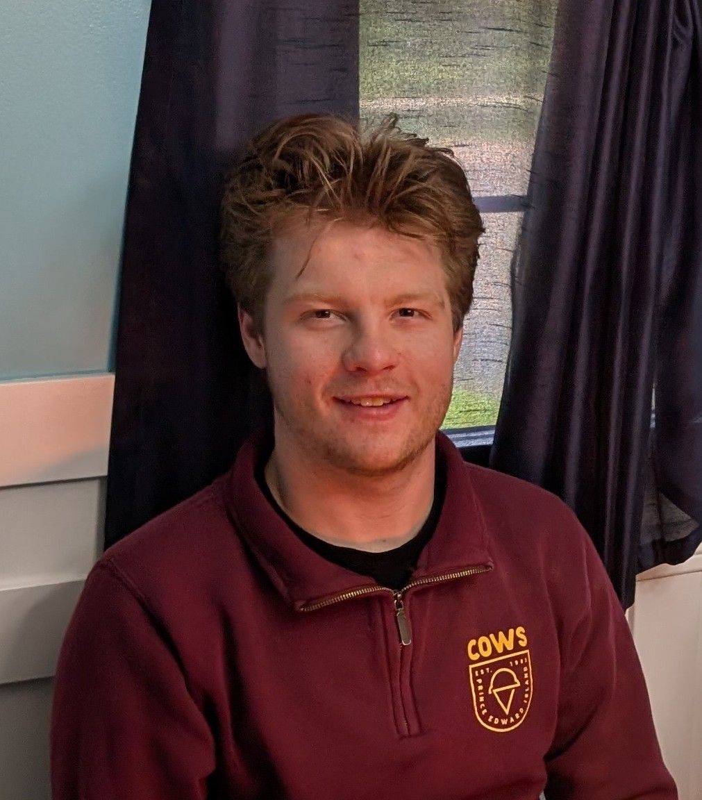 Nicholas, smiling, in a maroon quarter-zip