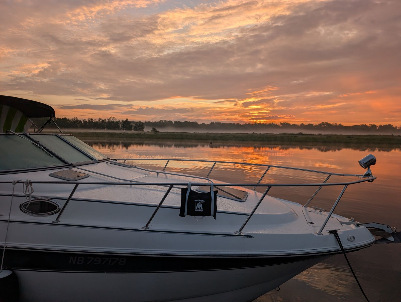 Sunrise over the river at Gagetown, with the bow of Island Belle and mist on the water