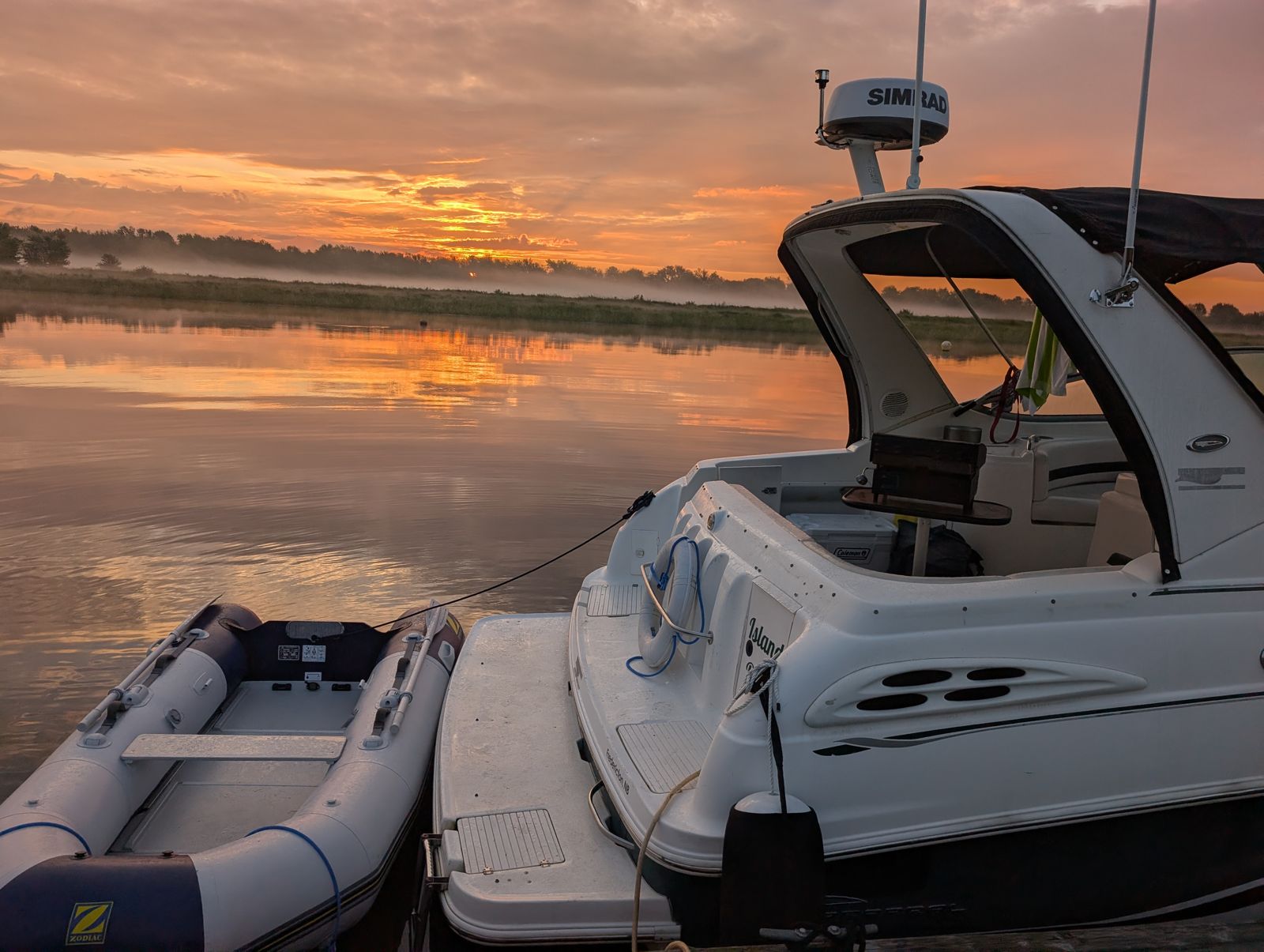 The stern of Island Belle at sunrise with the Simrad radar dome and the grey Zodiac alongside